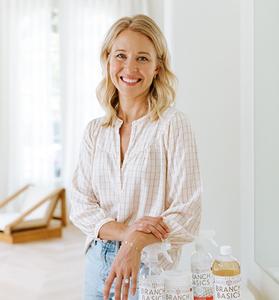 Founder Allison Evans standing with Branch Basics bottles