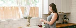 Woman in the kitchen washing produce with Branch Basics